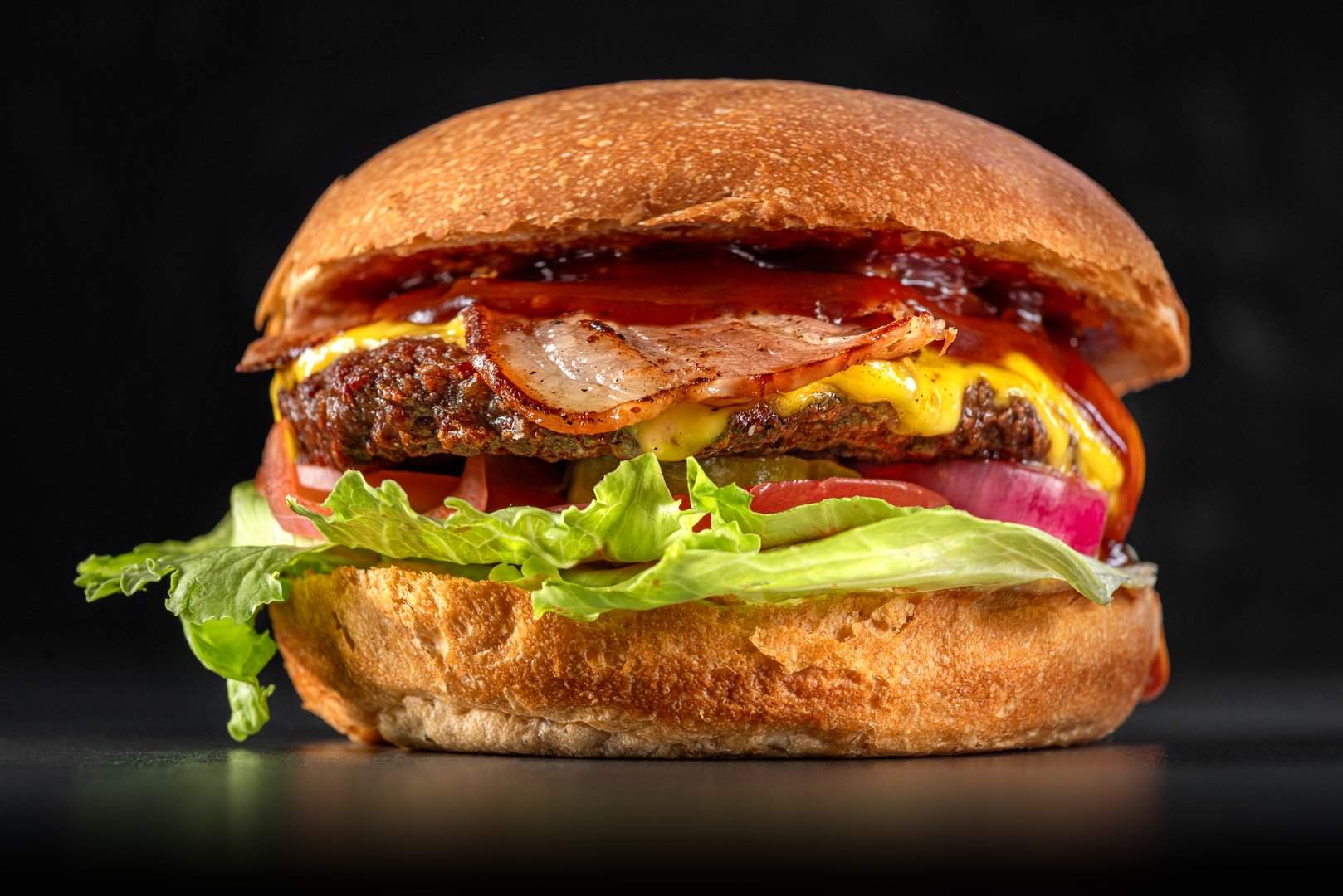 Bacon-Cheeseburger vor dunklem Hintergrund