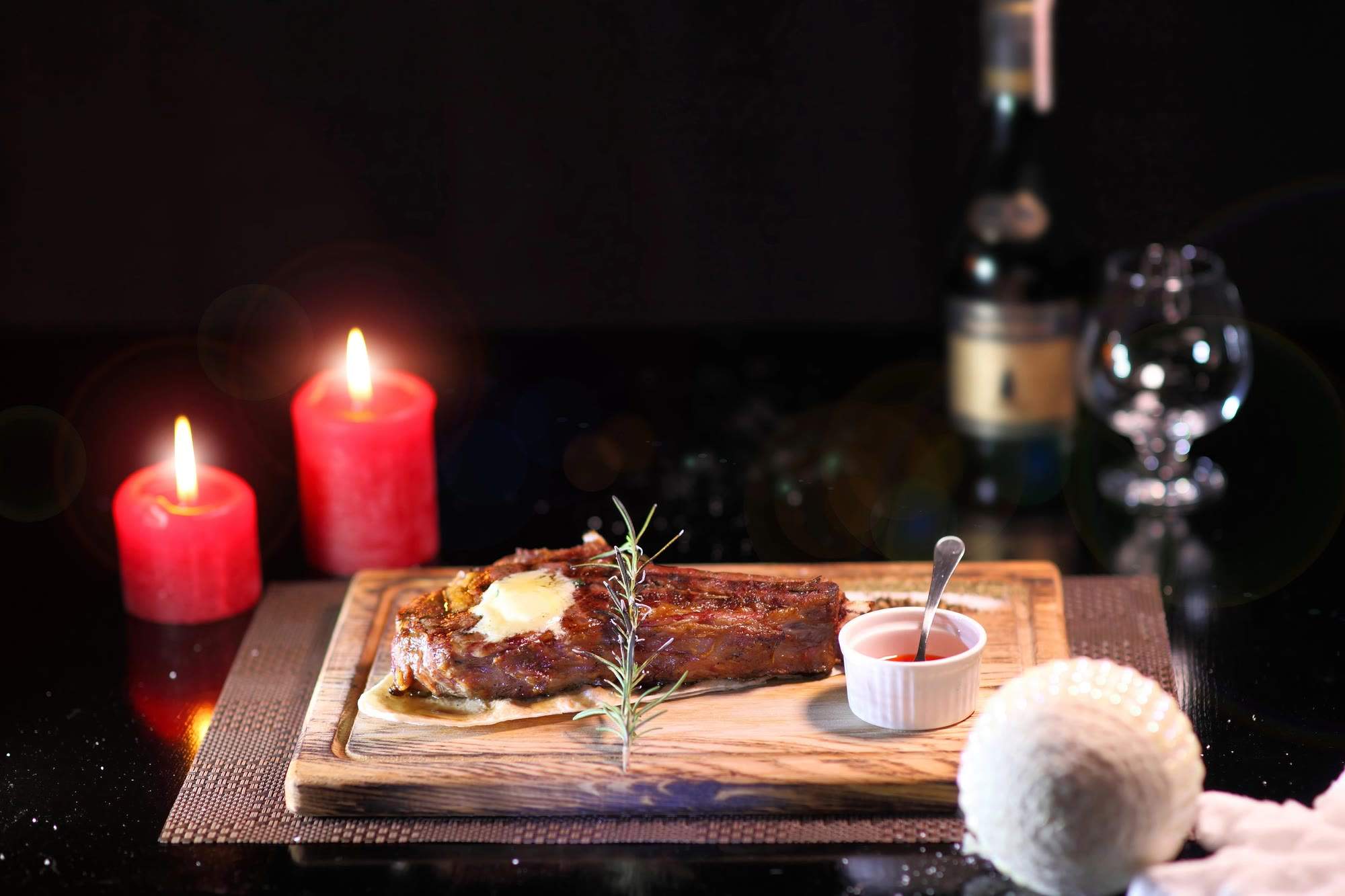 Steak auf einem Holzbrett bei Kerzenschein mit Rotwein